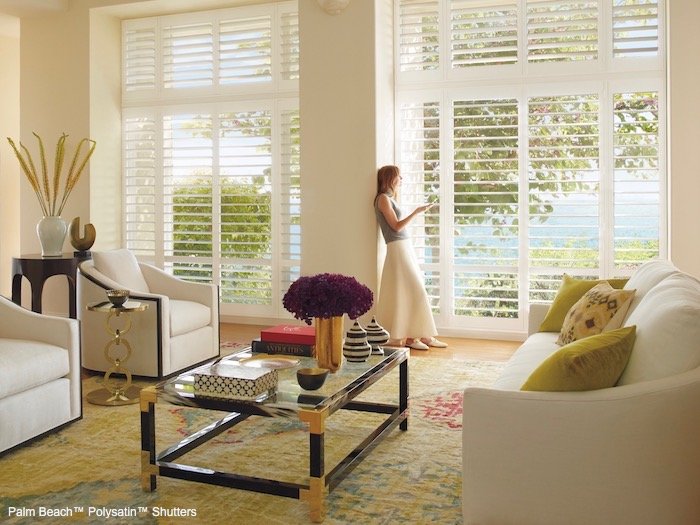 A living room with green accents. Shown with Palm Beach Polysatin Shutters; available at F & R Blinds, Inc in Los Angeles
